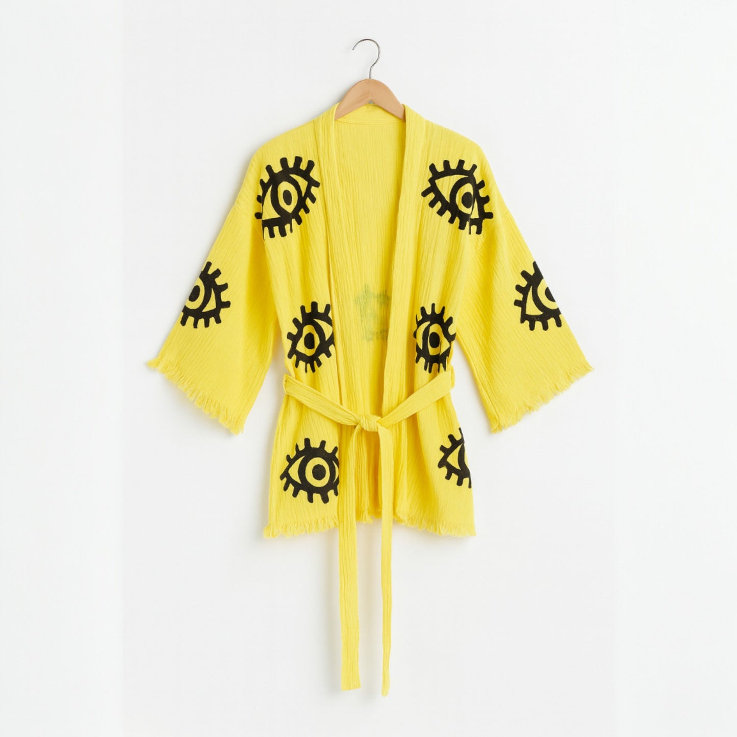 Yellow robe with black patterns on a hanger against a white background