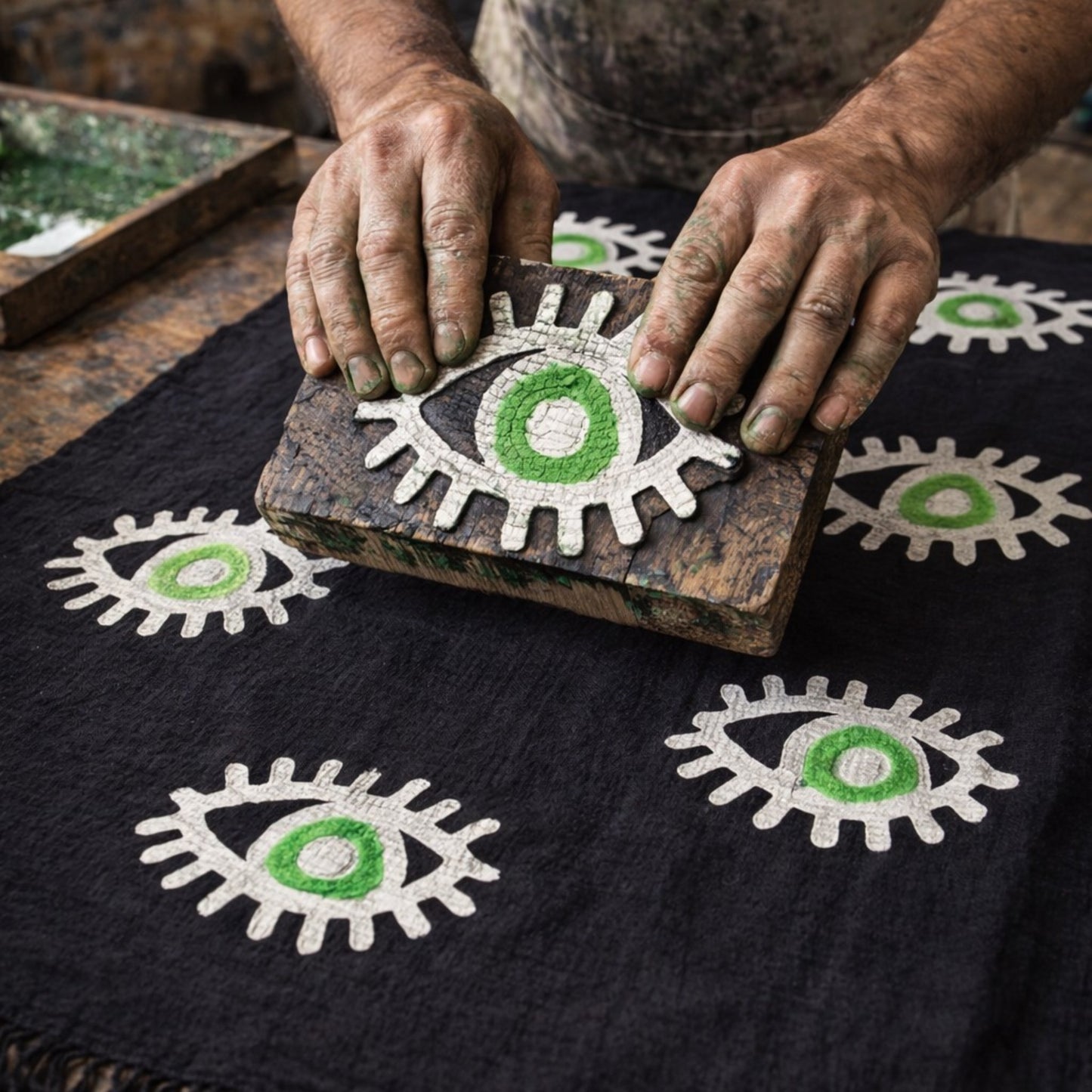 Person using a wooden block to print eye designs on fabric to make hand woven evil eye turkish cotton kimono robe black