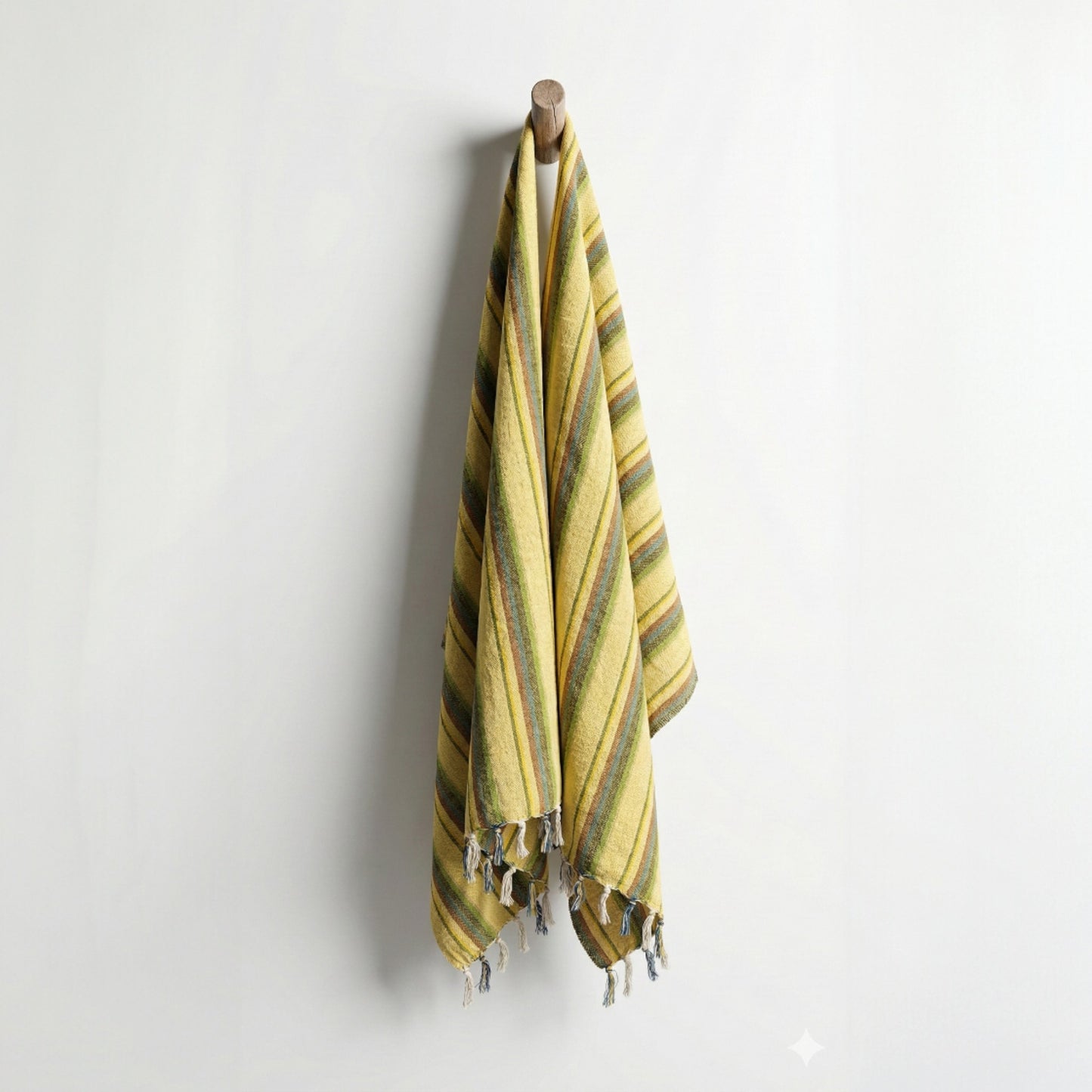 Yellow and green striped Hand-woven linen Turkish towel pestemal hanging on a wooden hook against a white wall