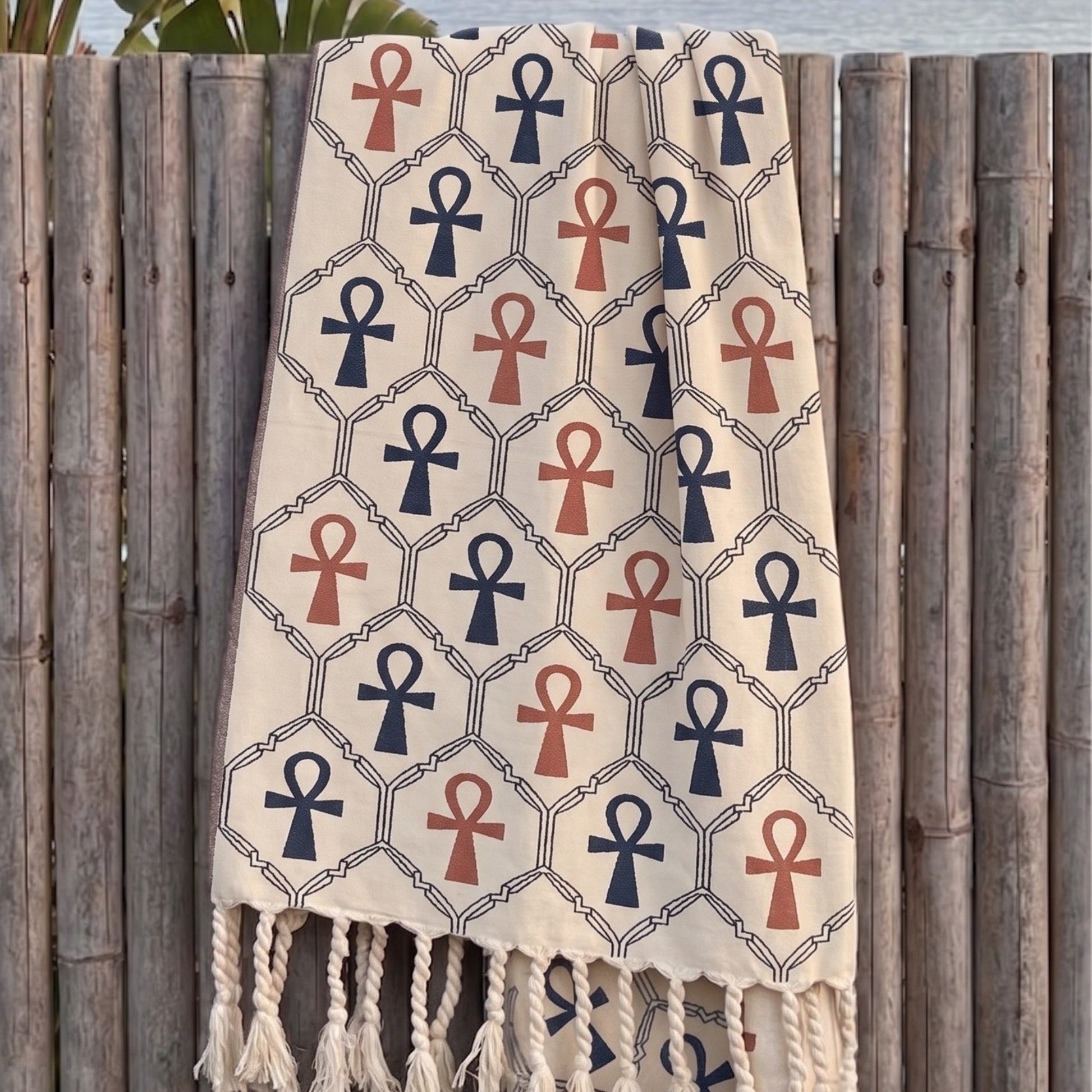 Beige ankh turkish towel pestemal reversible beach towel hanging on a wooden fence