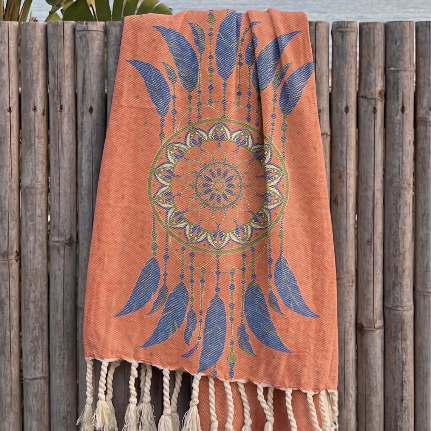 Orange eco friendly handmade boho pestemal towel over a wooden fence.