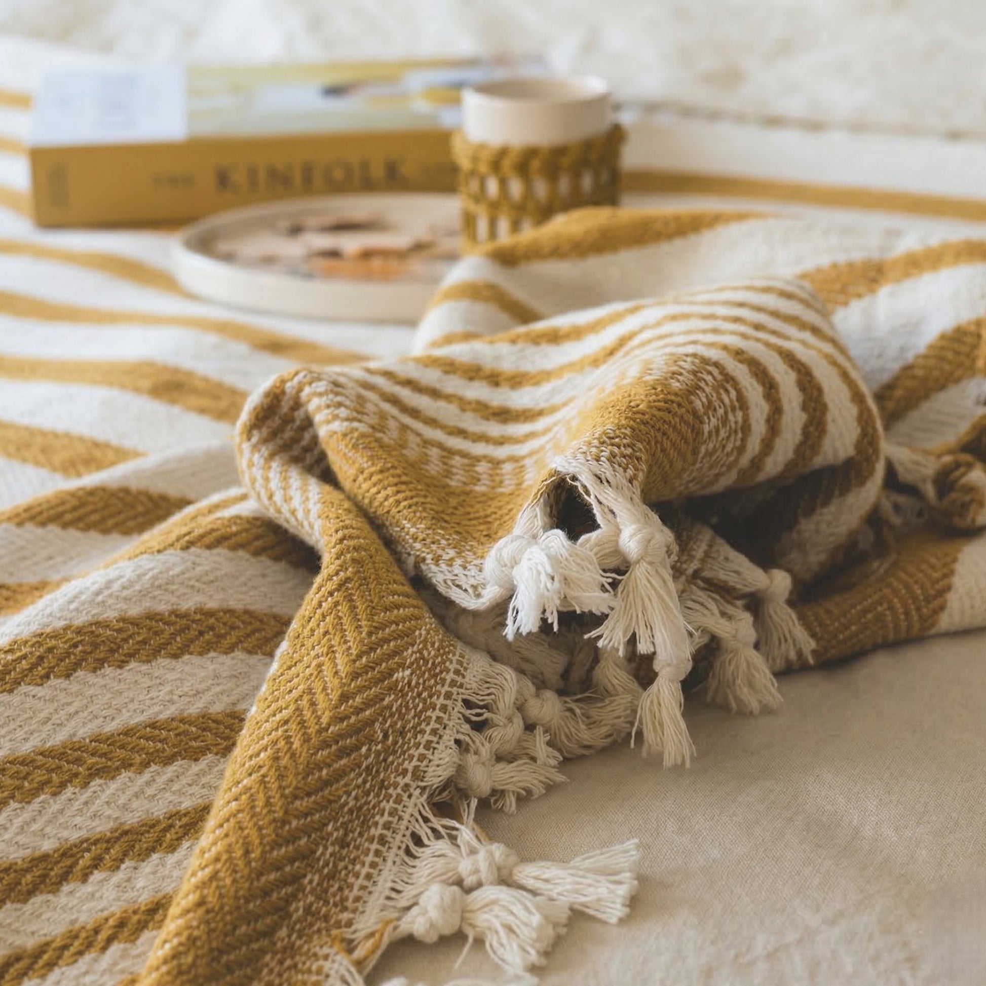 Mustard Yellow and white striped blanket with tassels on a table
