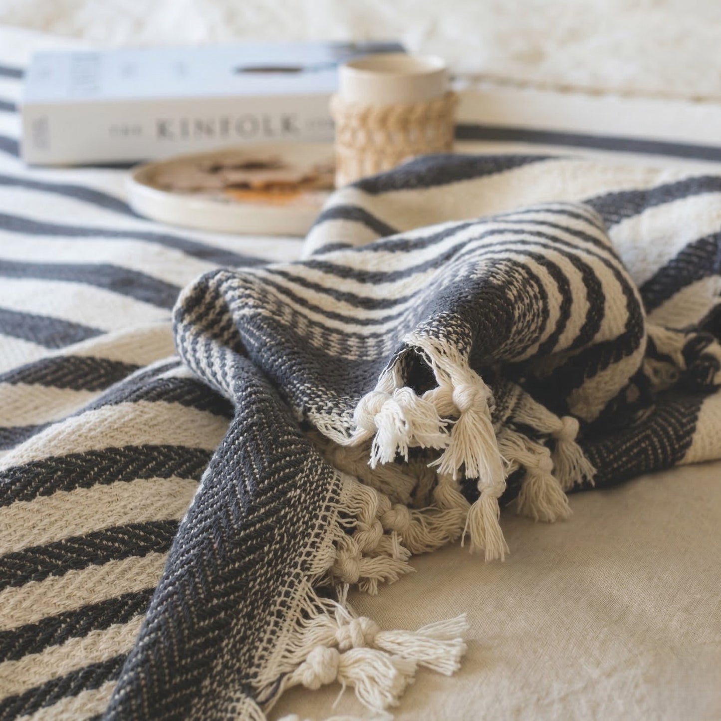 Textured blanket with tassels on a striped surface