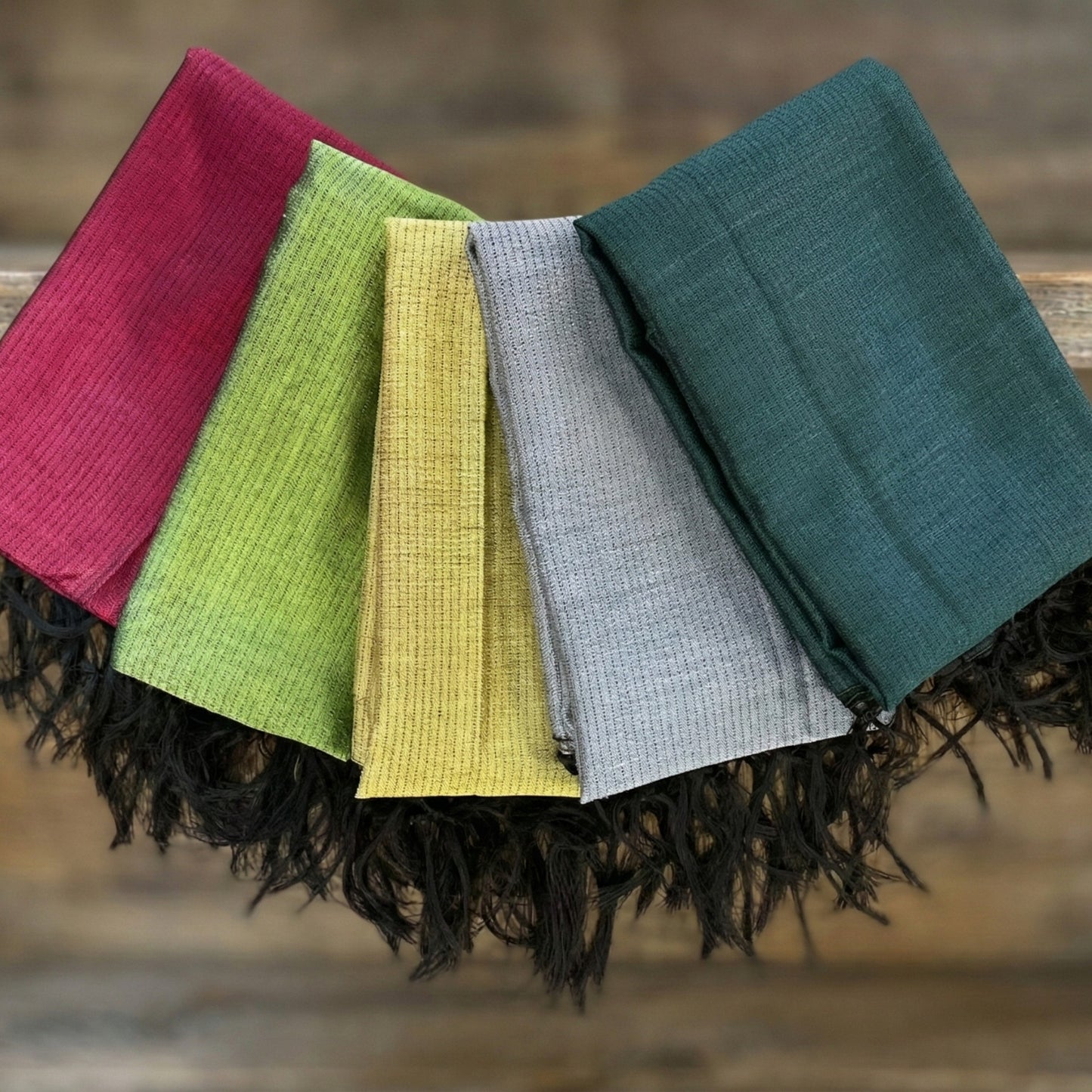 Five Antakya Handwoven Silk Scarves in different colors arranged on a wooden surface.