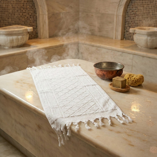 Hand-woven Baklava Design Turkish hand towel with traditional diamond pattern on a marble surface in a Turkish Hammam Turkish Bath.
