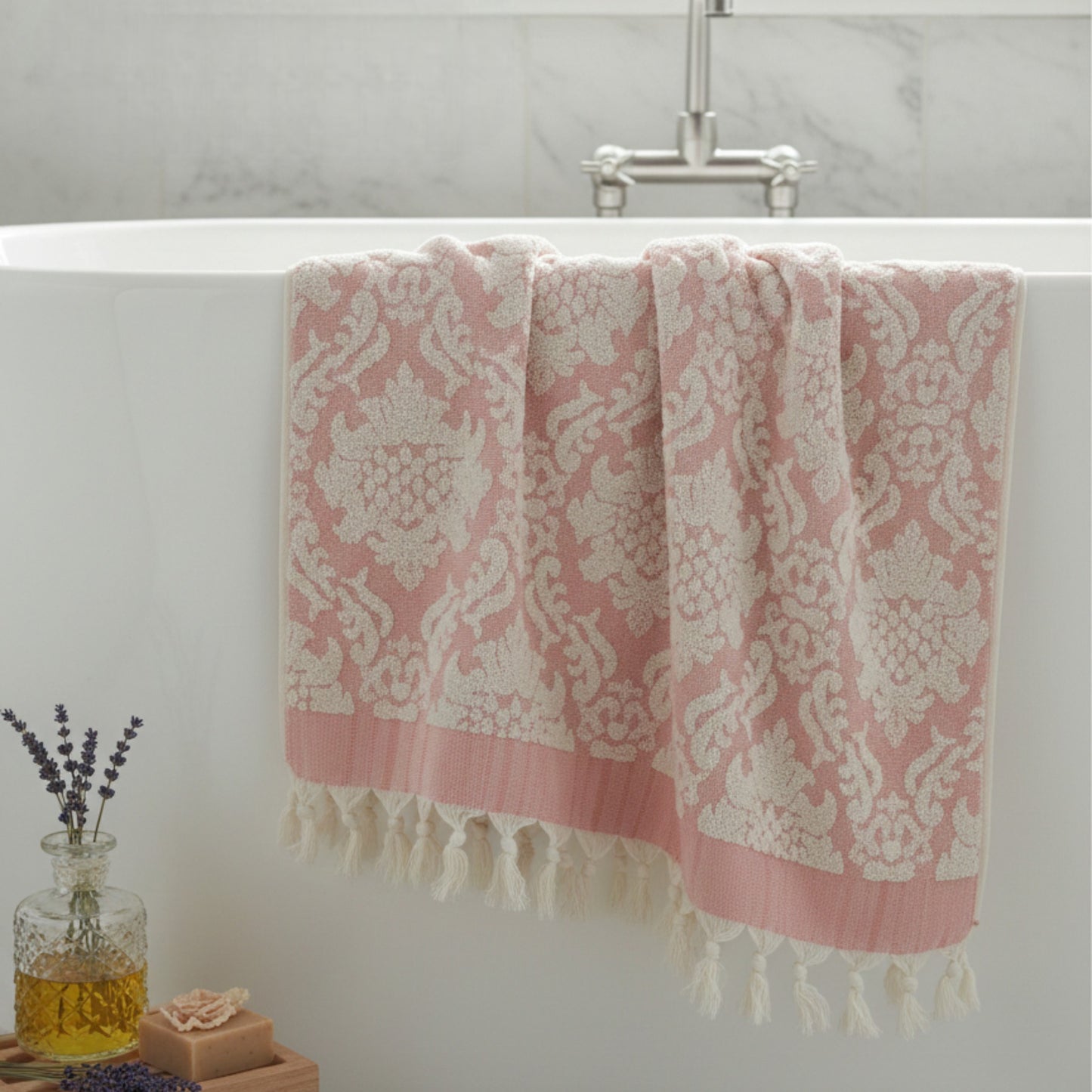 Pink and white Damascus Design Natural Cotton Turkish Terry Bath Towel hanging over a bathtub with a vase of lavender and soap on the edge.