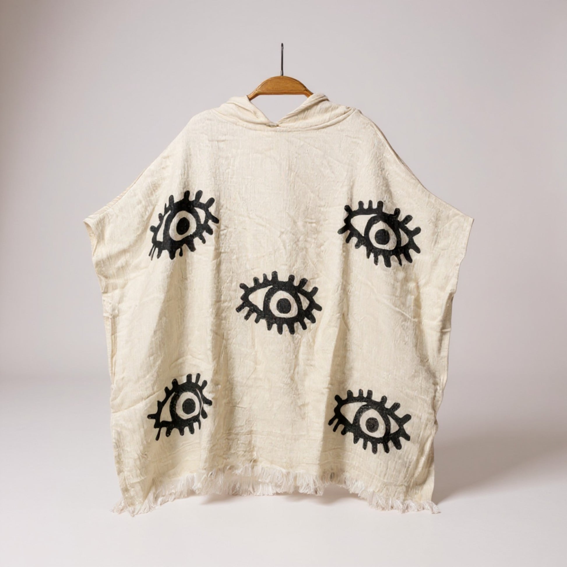Beige sleeveless top with black eye patterns on a white background