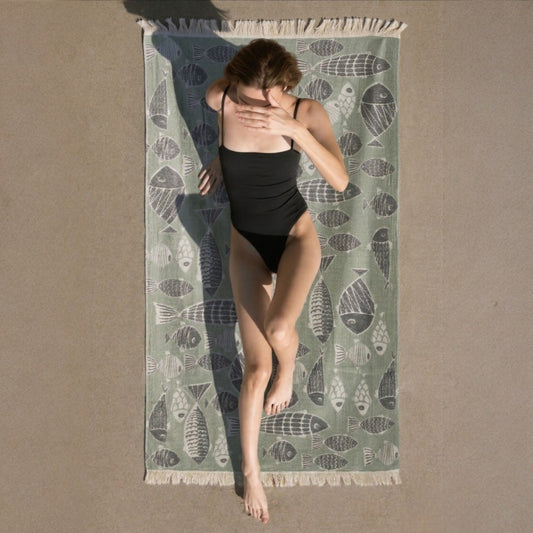 Person in a black swimsuit standing on a patterned Fish Pattern 3-Layer Turkish Towel – Jacquard Woven Muslin Beach Towel