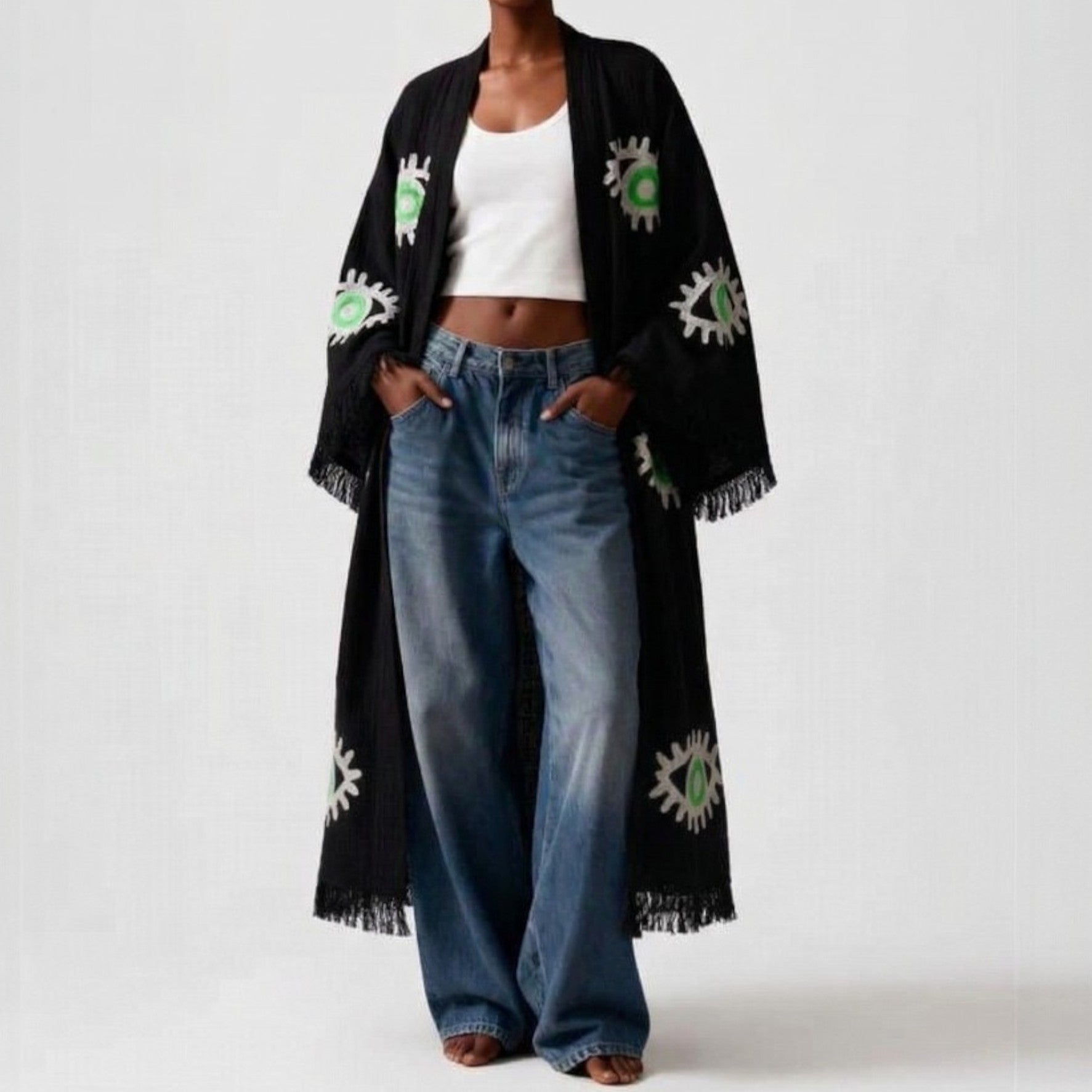 Person wearing a hand woven evil eye turkish cotton kimono robe black and blue jeans on a white background
