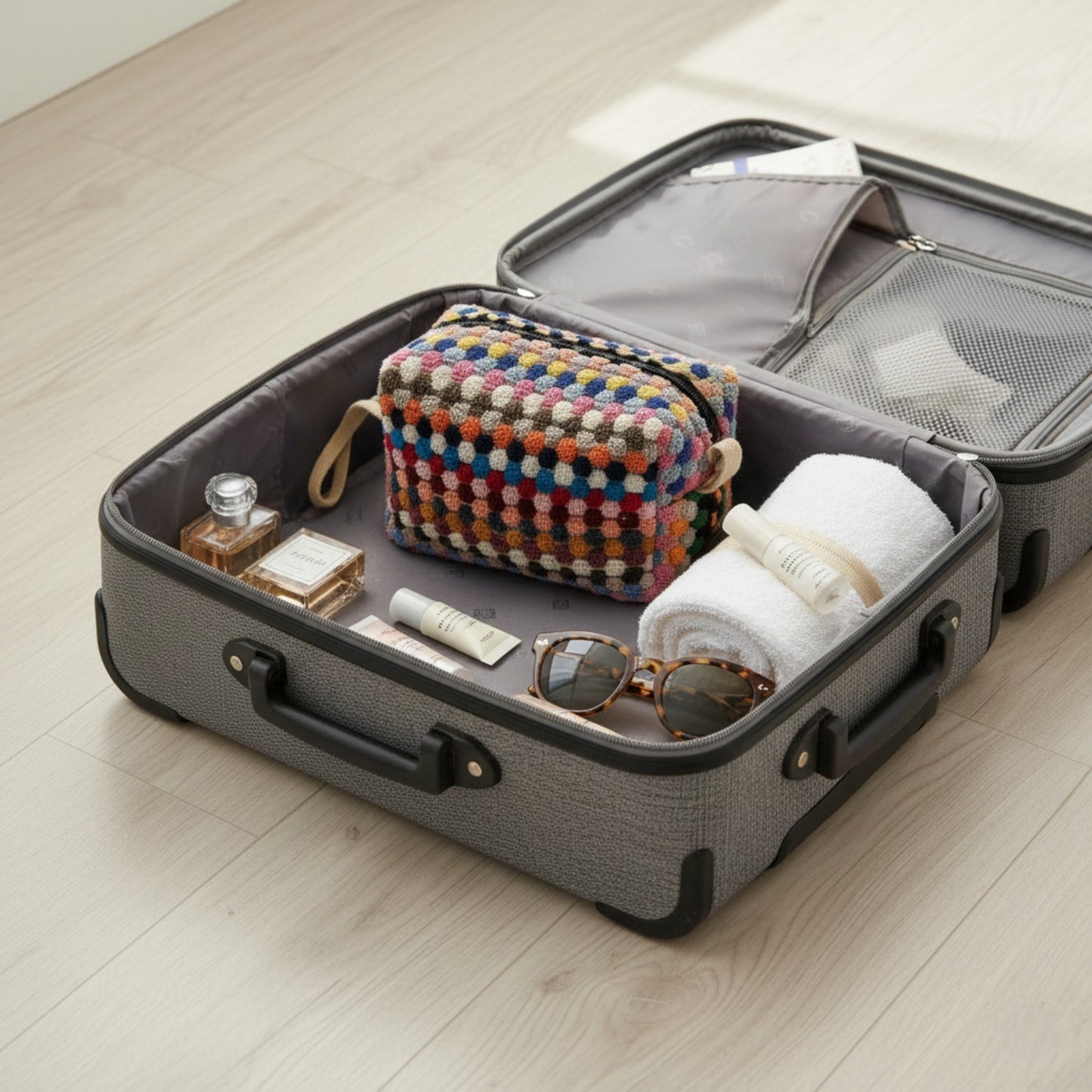 Open suitcase with travel items with Handmade travel makeup pouch with natural cotton dotted texture on a light wooden floor