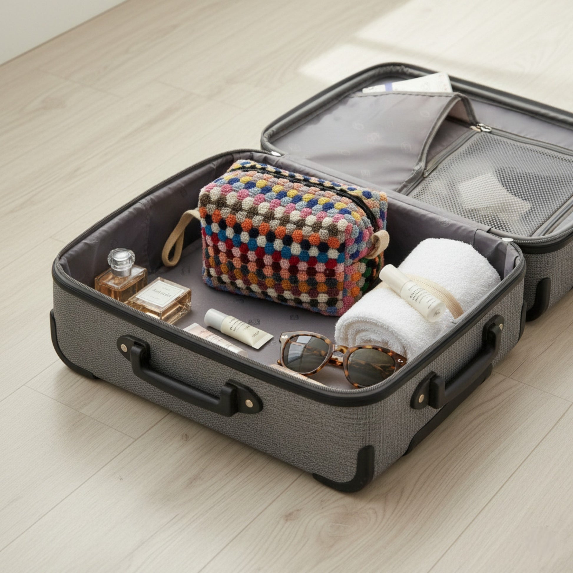 Open suitcase with travel items with Handmade travel makeup pouch with natural cotton dotted texture on a light wooden floor