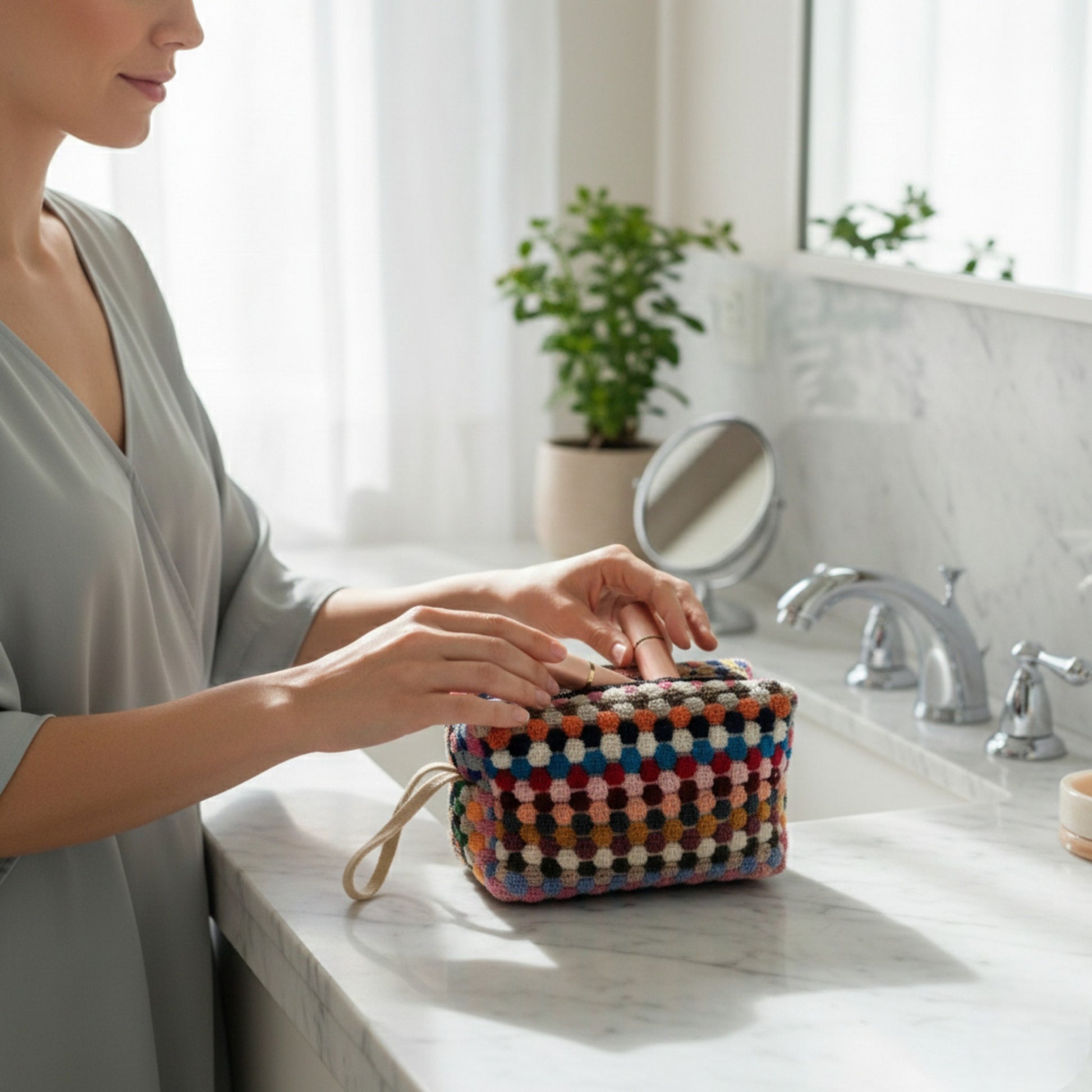 Person interacting with a colorful woven Handmade travel makeup pouch with natural cotton dotted texture on a bathroom counter.