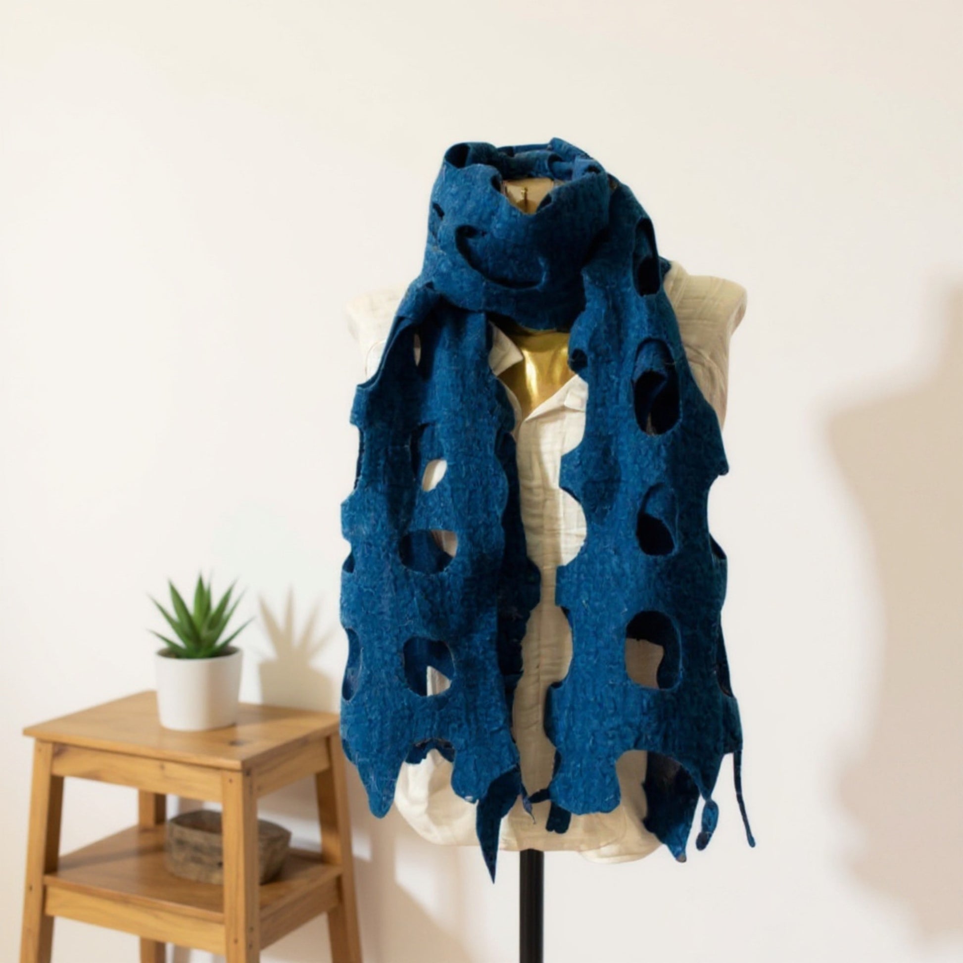 Handmade felted wool shawl/scarf in indigo blue, displayed on a mannequin with cut-out design, soft textured fabric, 35x95 cm