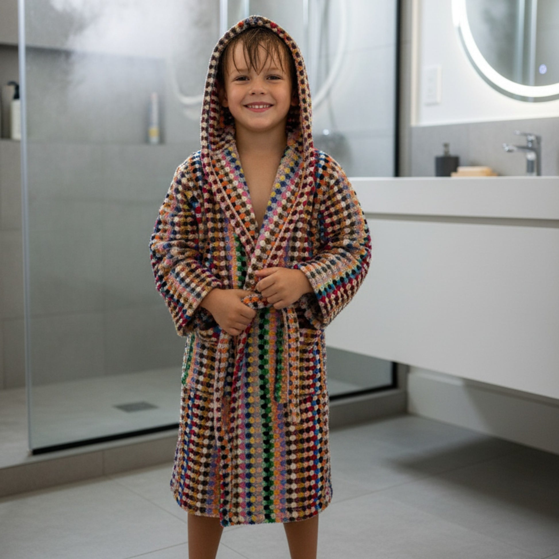 Child wearing a colorful robe in a bathroom