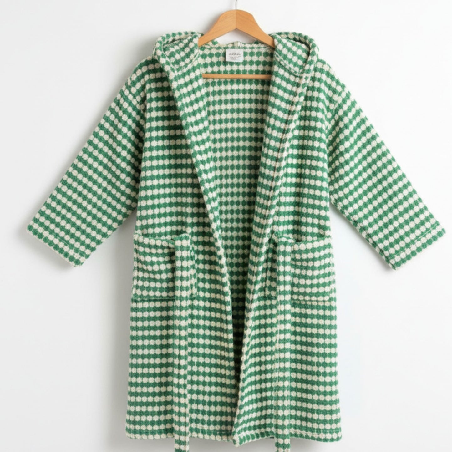 Green and white checkered robe on a wooden hanger against a white background