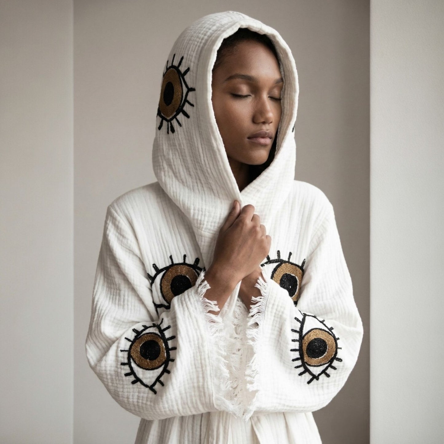Person wearing a Hooded Turkish Towel Kimono Robe – Handwoven Muslin Cotton, Brown Evil Eye Design on a neutral background