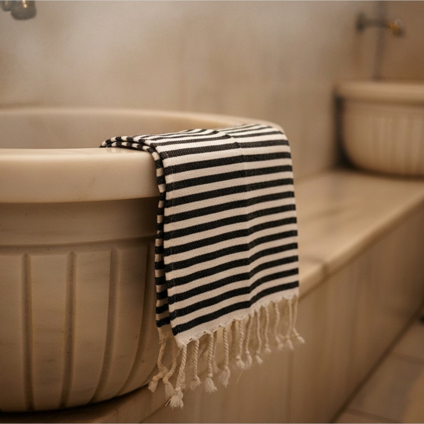 Black and white striped Natural Cotton Traditional Hand Towel draped over a bathtub in a bathroom setting