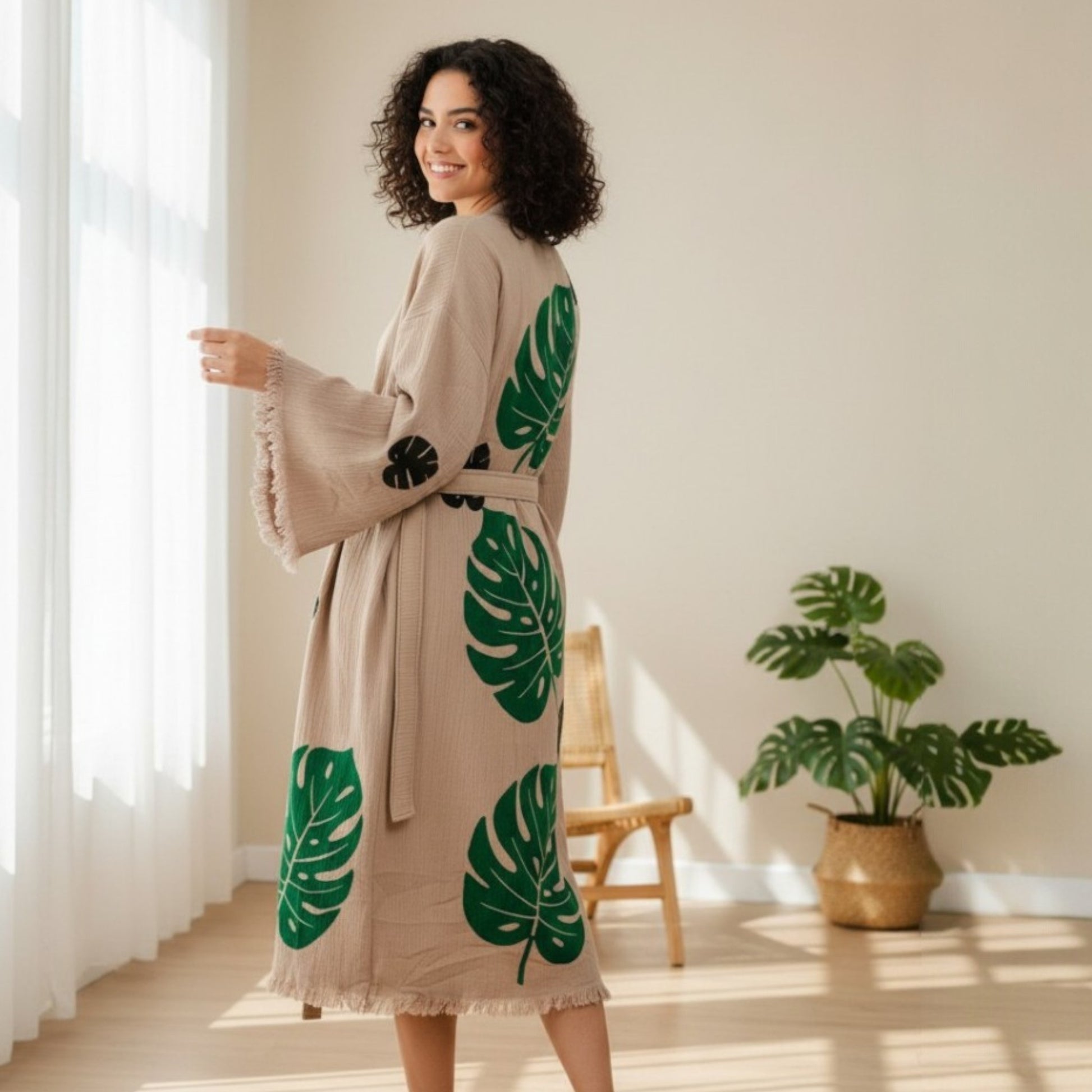 Woman wearing a beige Turkish Towel Kimono Robe – Hand Block Printed Natural Cotton Kimono | Evil Eye Kimono Robe Collection in a bright room with a plant.