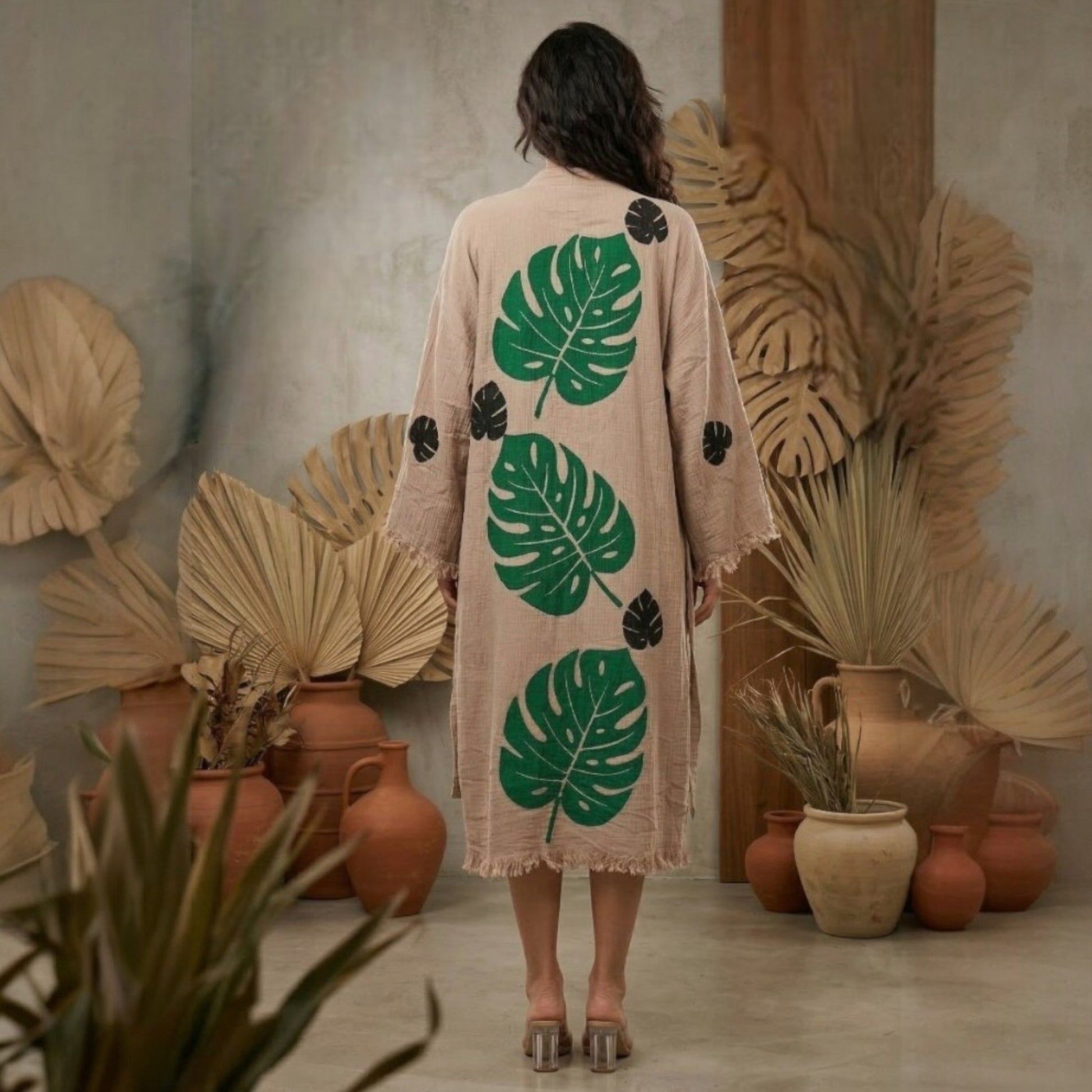 Person wearing a beige Turkish Towel Kimono Robe – Hand Block Printed Natural Cotton Kimono | Evil Eye Kimono Robe Collection in a room with plants and pots.