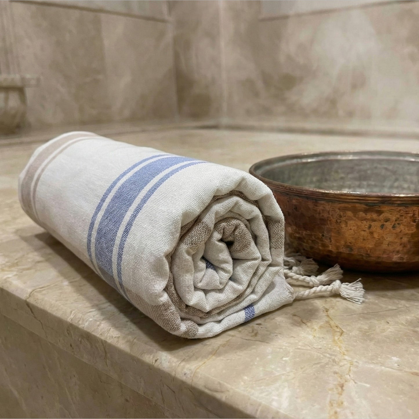 Rolled Traditional Turkish Peşkir — Hand-Woven, Hand-Knotted, Natural Cotton with blue stripes on a marble surface