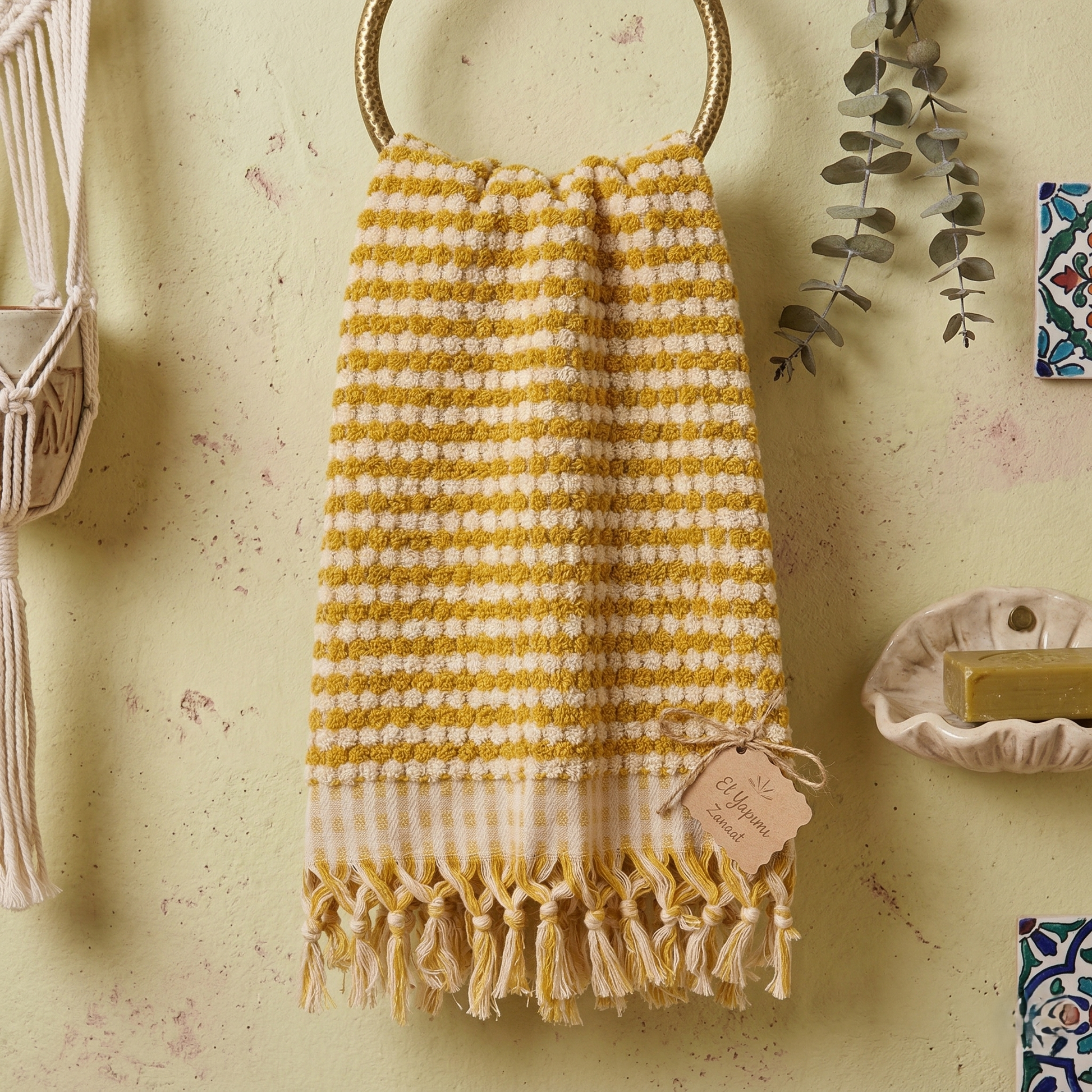 Golden Dotted Turkish Terry Towel, Handwoven Luxury Cotton hanging on a ring against a textured wall with decorative elements.